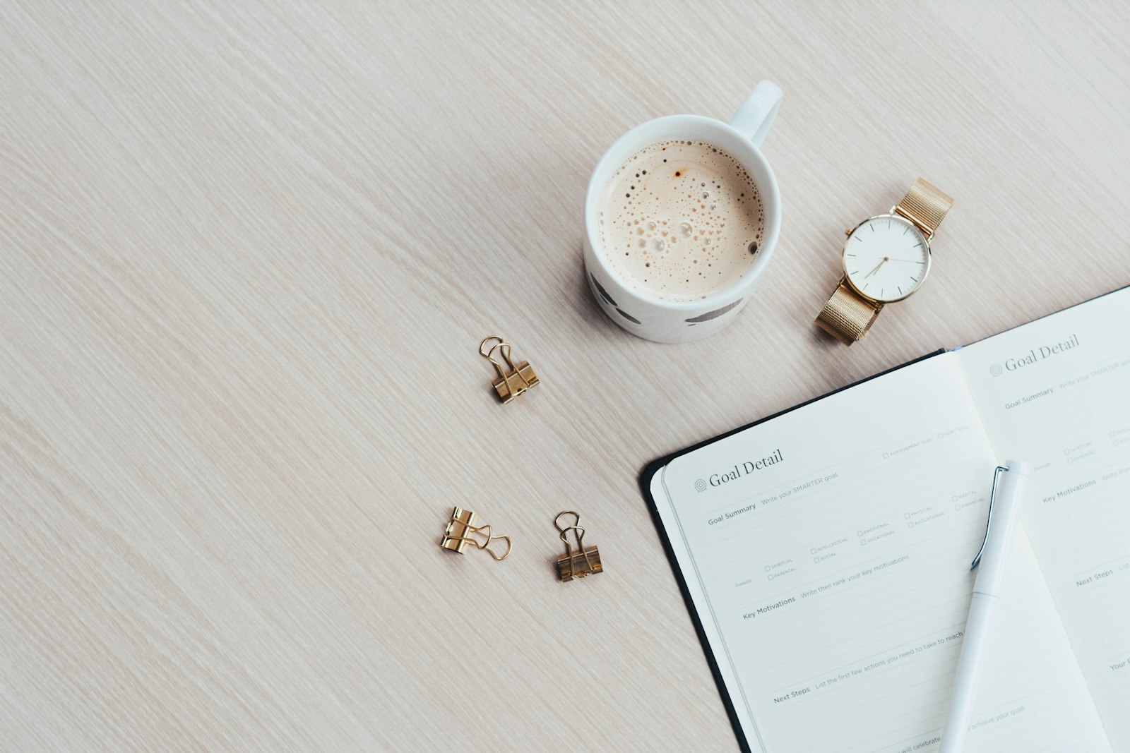 A journal, coffee, and everyday tools laid out on a desk, ready for a real work session